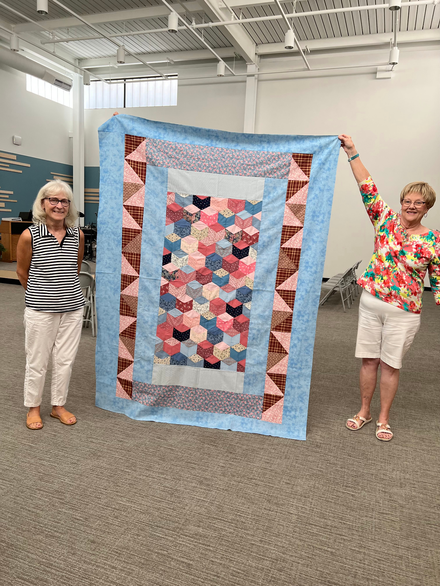 Handmade quilt displayed by two women