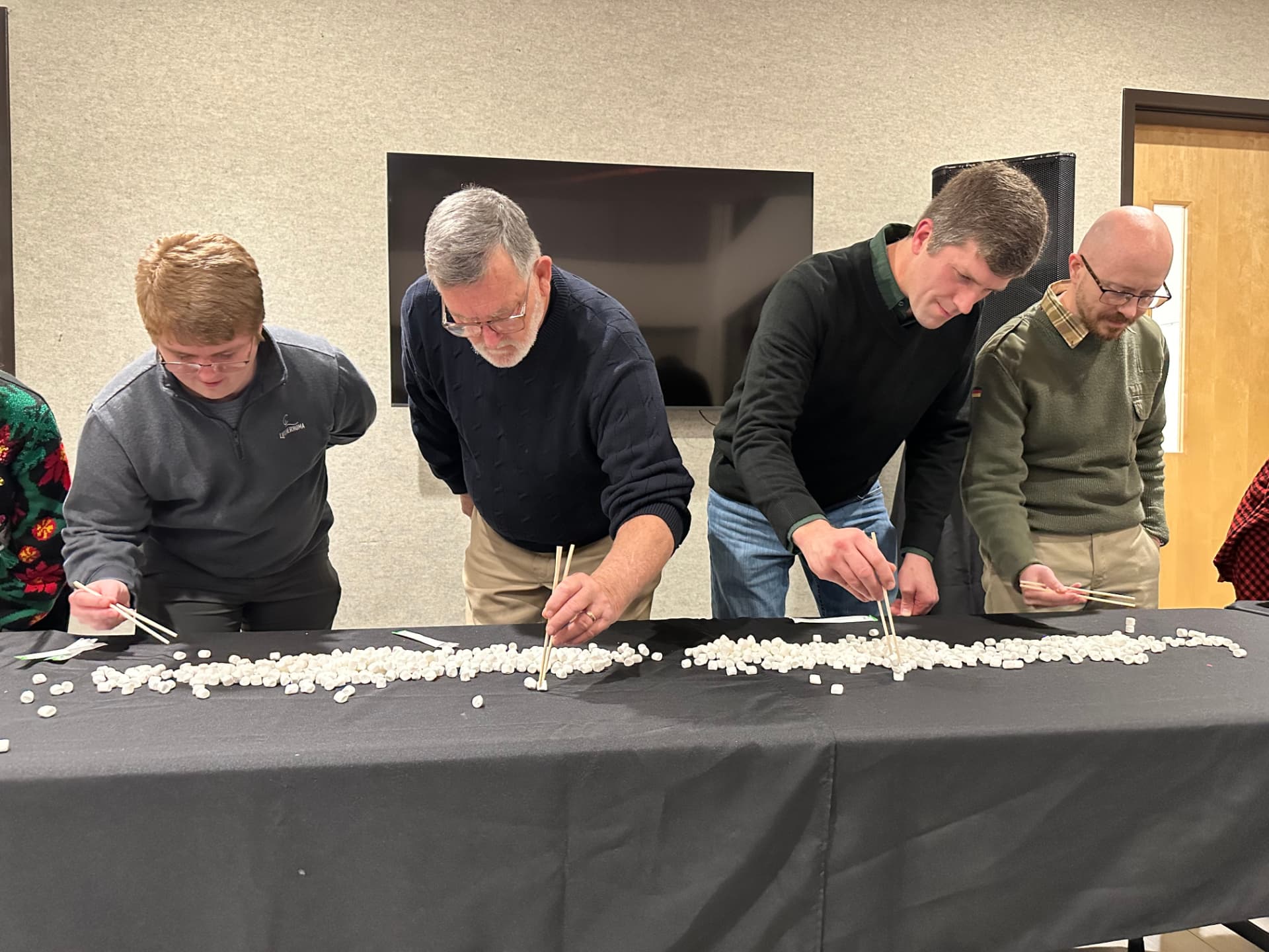 Men competing in a marshmallow and chopsticks Christmas party game