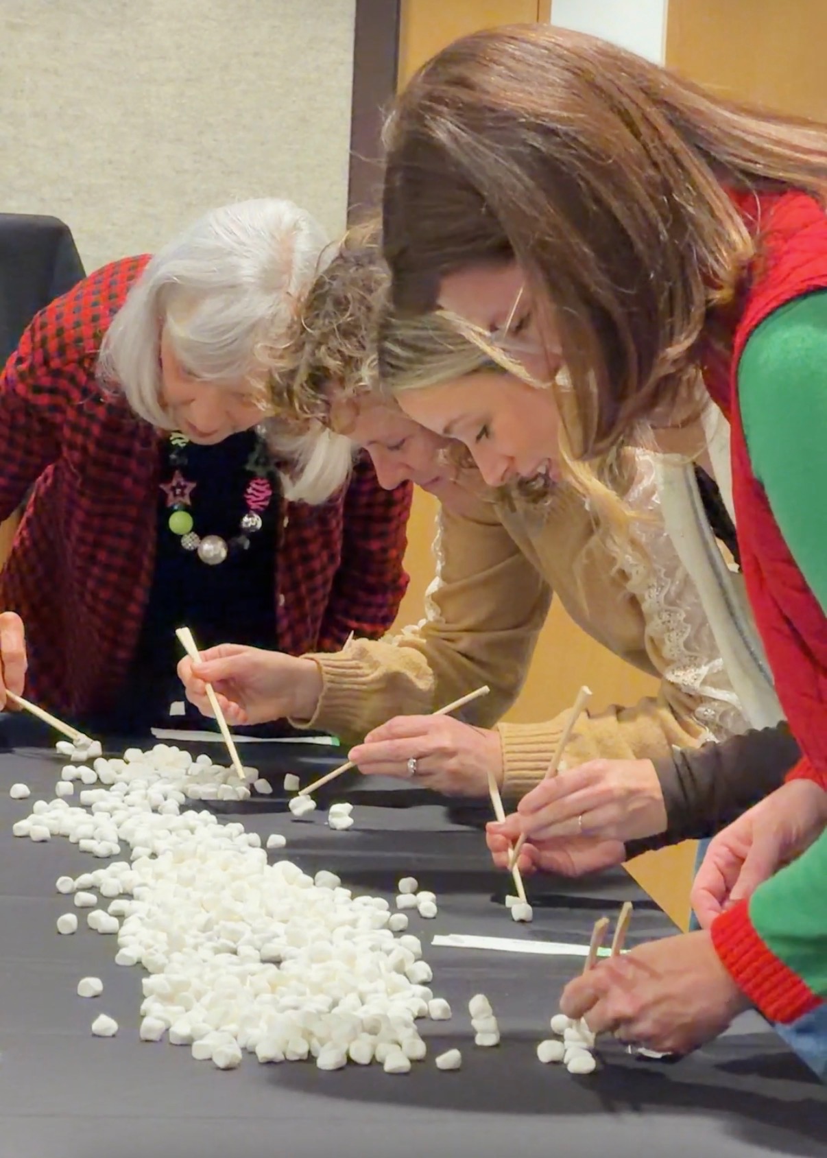 Women competing in a marshmallow and chopsticks Christmas party game