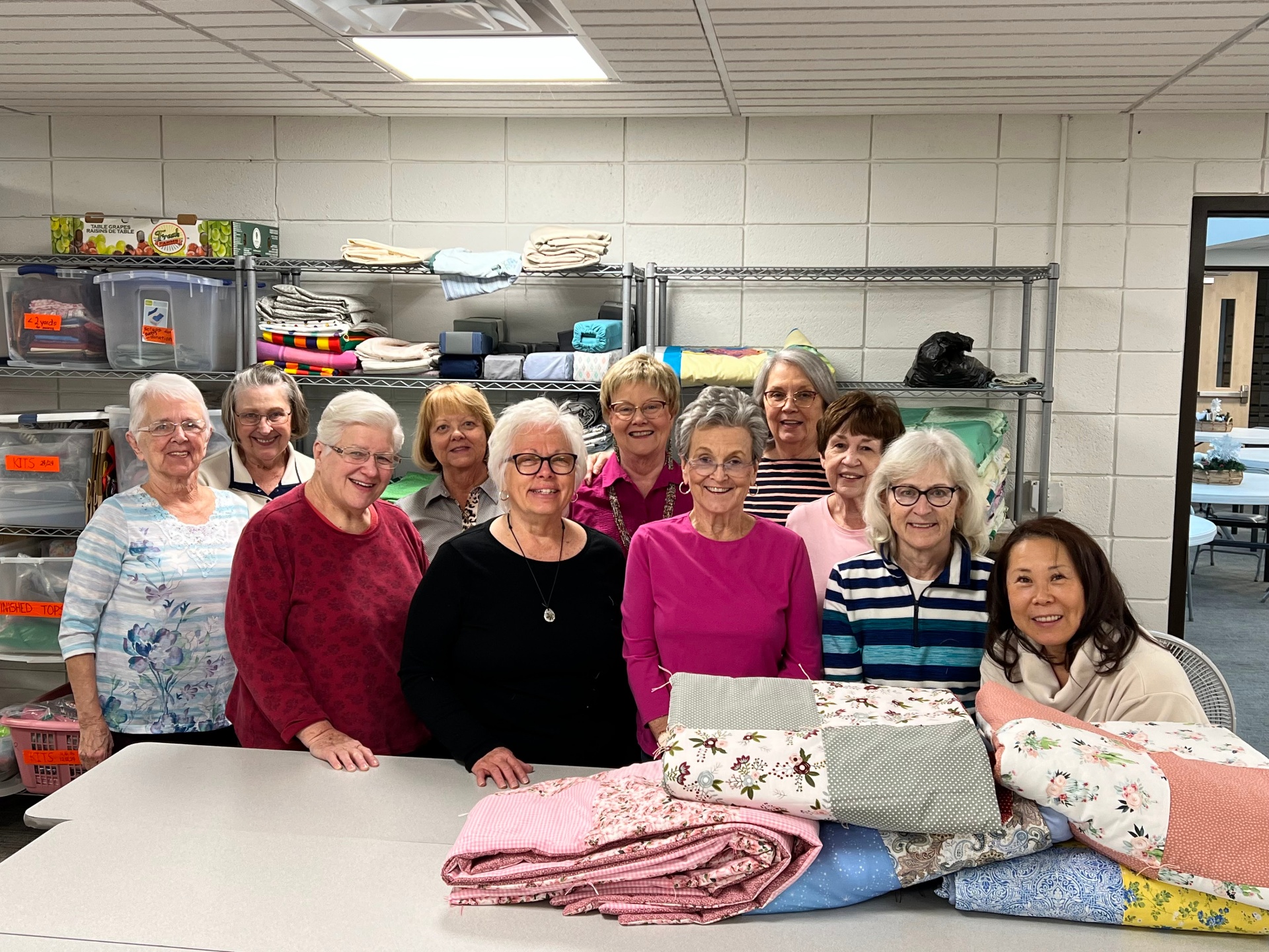 Quilters ministry group with finished quilts